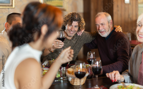 Multi-generation family discussing daily life while having fresh food and wine in restaurant