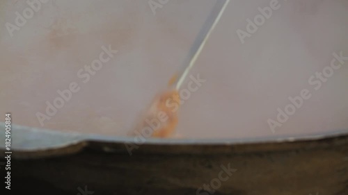 A close-up of a boiling pot of borscht with finely chopped ingredients, steam escaping. A ladle stirs the contents