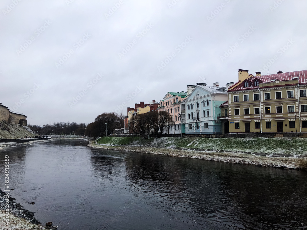 Obraz premium Winter scene along the Pskova River embankment in the city of Pskov, Russia. The Golden Embankment covered in snow creates a calm atmosphere, concept of seasonal tourism and cold weather charm.
