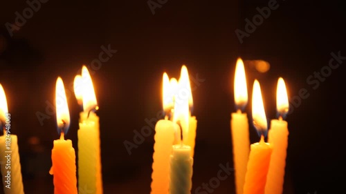 Candles flame burning on a birthday cake on dark background
