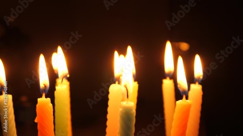 Candles flame burning on a birthday cake on dark background