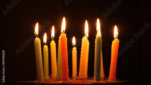 Candles flame burning on a birthday cake on dark background