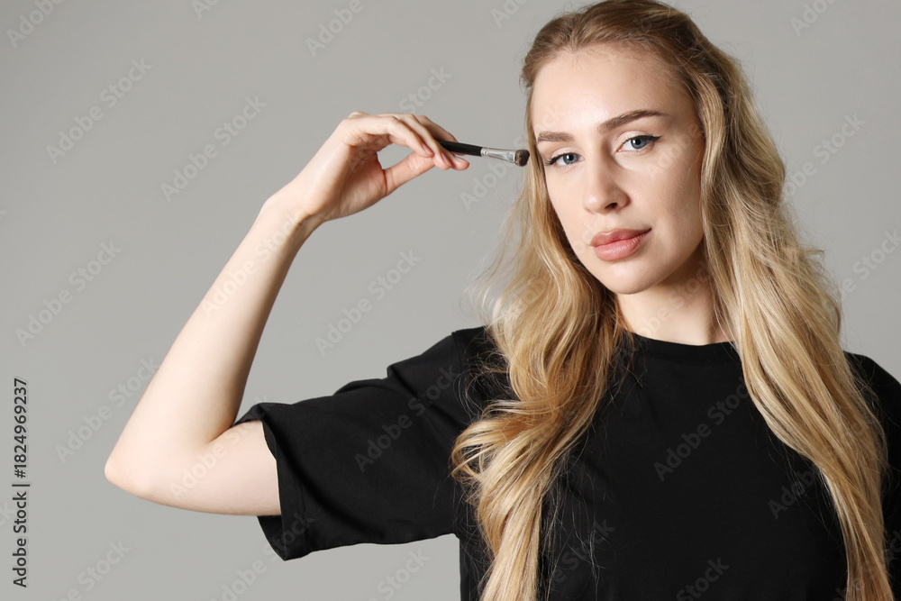 Obraz premium Makeup artist with brush on light grey background