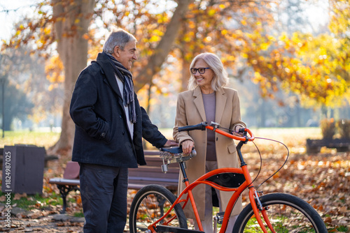 Happy senior couple enjoying a bike ride in the autumn park on a sunny day