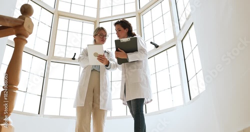 Doctor consulting intern in clinic, concluding meeting with handshake