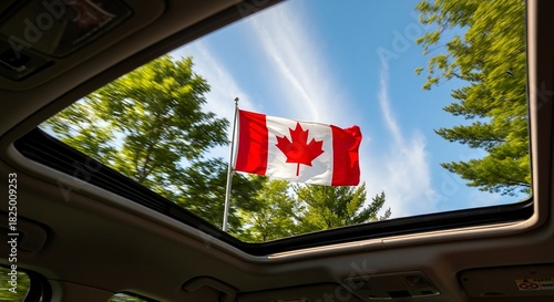 View of the Canadian flag waving from a moving car's open sunroof. Patriotic road trip and travel in Canada on a sunny summer day
