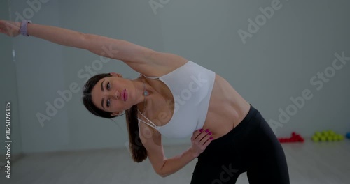Athletic girl training flexibility gym doing lateral bending motion focused expression