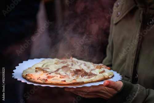 Person holds a tarte flambee flammekueche, Christmas market, Strasbourg, France