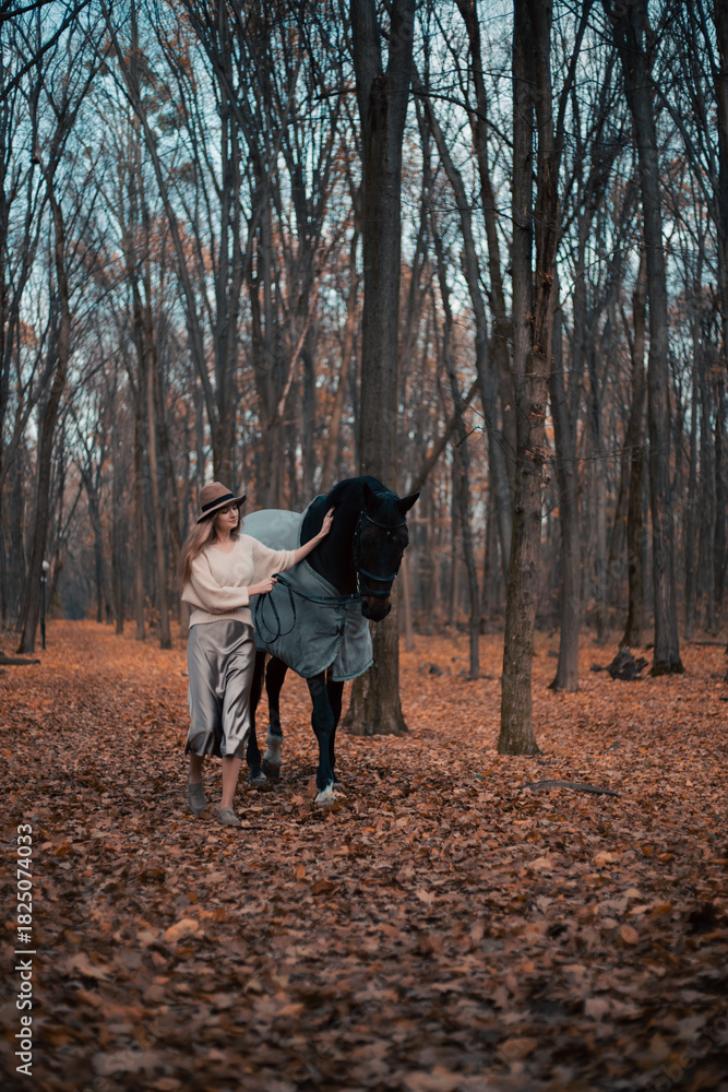 Fototapeta premium Walking with a horse through a forest path during autumn in the late afternoon