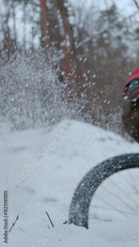 SLOW MOTION: Mountain biker sprays snow while riding corner at snowy forest trail. Fun bike ride in the woods after fresh snowfall. Spice of adrenaline during mountain biking in winter conditions.