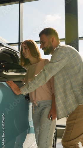 Happy couple choosing new car at showroom