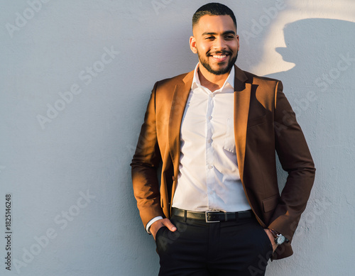 Confident young businessman enjoying a moment of reflection in the sunlight, showcasing success and leadership with a genuine smile and stylish attire