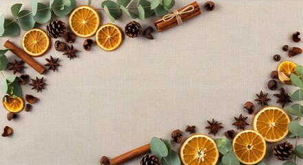 Winter holiday background with dried orange slices star anise spices cinnamon sticks pine cones and eucalyptus leaves arranged on neutral beige fabric backdrop forming decorative frame border