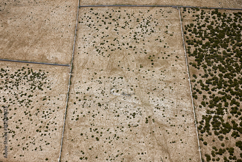 Aerial view of arid fields divided by stone walls creating a patchwork of textures and tones under the harsh sun, Pag, Croatia.