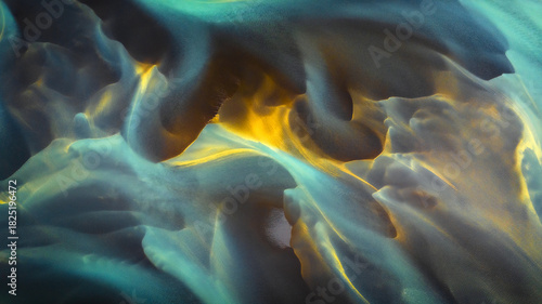 Aerial view of glacial river patterns display a mesmerizing swirl of turquoise, gold, and grey hues creating an ethereal landscape, Hvolsvollur, Rangarbing eystra, Iceland.