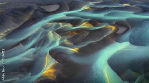 Aerial view of glacial rivers carve through the volcanic sands, a tapestry of turquoise and gold against the stark, grey landscape., Hvolsvollur, Rangarbing eystra, Iceland.