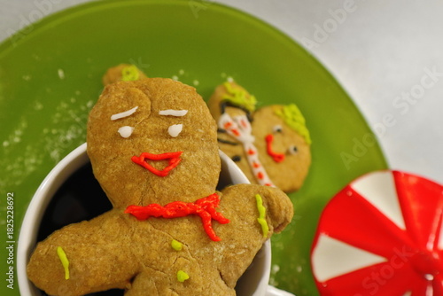 Decorated gingerbread men on a green plate with a white coffee mug