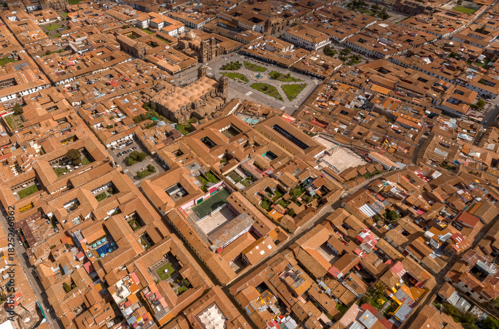 Fototapeta premium Aerial view of the dense historic center of Cusco, Peru. Features the Plaza de Armas and a geometric pattern of colonial red tile roofs and internal courtyards (patios).