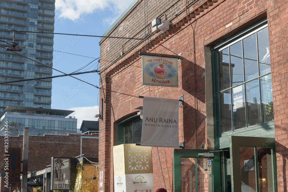 Fototapeta premium projecting signs outside The Sweet Escape and Anu Raina located at 24 Tank House Lane, Distillery District, Toronto