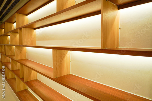 Modern wooden shelves with warm built-in lighting in a minimalist interior space