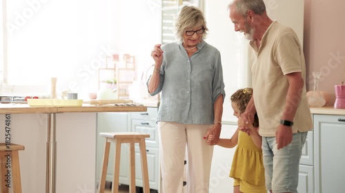 Happy senior couple accompanying their cute curly-haired granddaughter to the door as she leaves for school with her backpack on