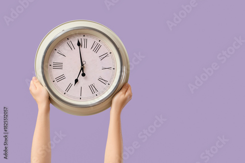 Принти на полотні Female hands holding wall clock on lilac background