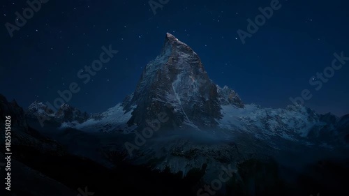 Majestic Mountain Peak Illuminated by Sunrise Over Snowy Landscape.