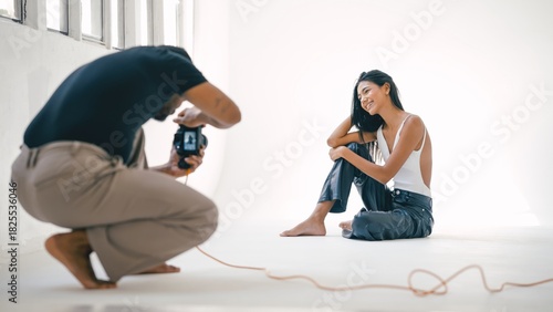 Photographer taking photos of a smiling model during a professional photoshoot in a bright studio