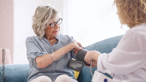 Obraz na płótnie Female doctor is using a sphygmomanometer for measuring blood pressure of a seni