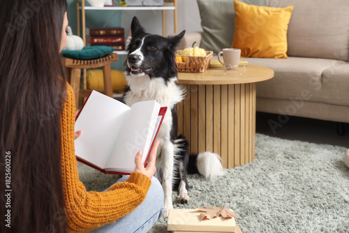 Young woman with blank book and Border Collie dog at home on autumn day