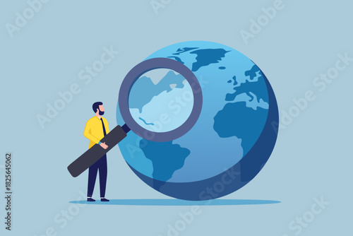 Global business strategy man with magnifying glass examining the world