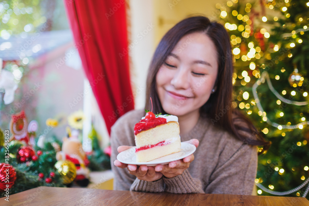 Fototapeta premium Portrait image of a woman holding a piece of cherry cake in Christmas holidays