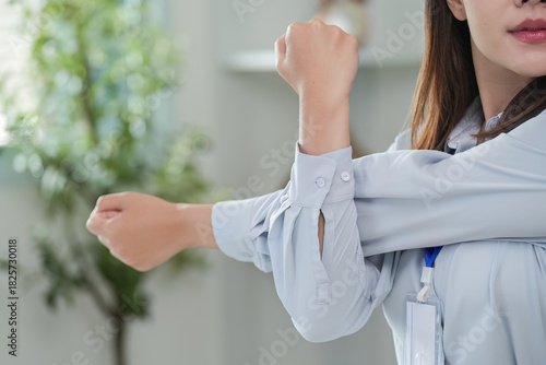 Arm stretching. Young woman stretching her arm at her desk.