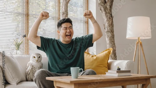 Excited Asian Man Cheering at Laptop Screen in Living Room