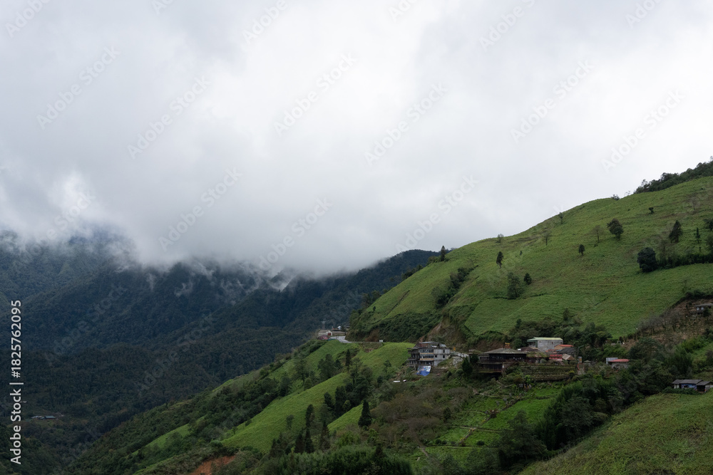 Fototapeta premium Mountain Village on Green Hillside under Cloudy Sky in Sa Pa, Vietnam