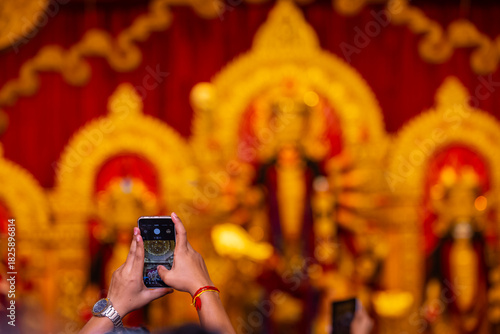 Canvas Print Hand holding mobile phone and taking photos of Goddess Durga idol at a pandal