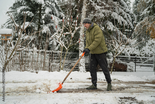 osoba odśnieżająca łopatą śnieg z chodnika