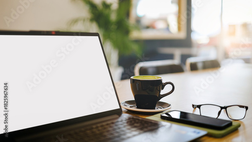 close up shot, desk office for meeting with blank screen laptop, mobile phone, coffee cup, and eyeglasses prepare for work and meetings