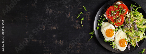 Fried egg, fresh salad and sandwich with tomatoes, pesto and cream cheese. Top view. banner