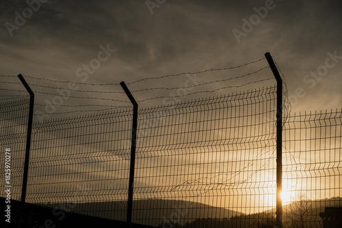 Border Fence at Sunset. Migration and Political Tension Concept