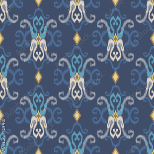 Seamless blue ikat pattern with ornate symmetrical motifs in cream and gold tones. Ideal for textiles, wallpapers, fashion fabrics, and digital design projects.