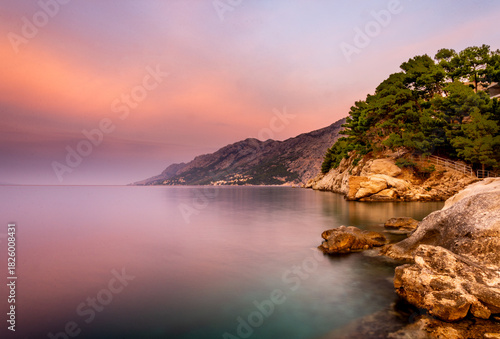 Fototapeta Naklejka Na Ścianę i Meble -  Croatian Adriatic coast on the Makarska Riviera at sunrise, with mountains and forests in the background.