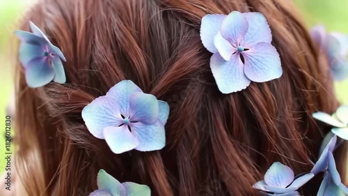 Close-up of a woman's hair adorned with delicate blue flowers in nature