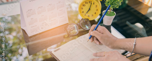 Close up of Female hand planner or organizer writing appointment on 2017 Calendar page.Woman mark and noted schedule on book or diary at office desk.Calendar reminder event concept.