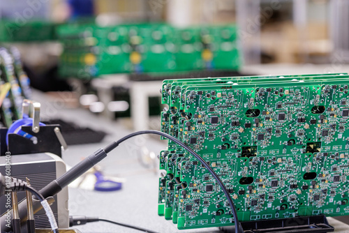 Electronics engineer testing printed circuit boards at industrial production line