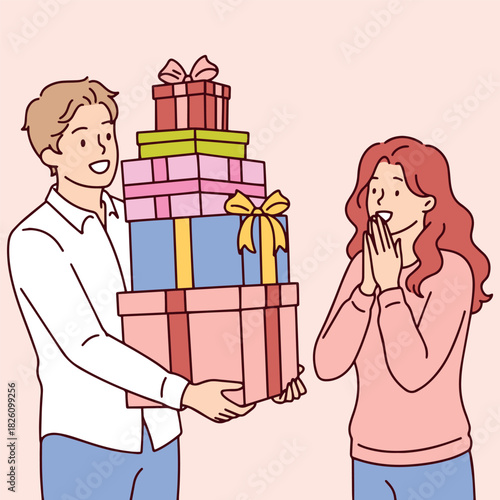 Happy boyfriend presents a pile of colorful gift boxes to his surprised girlfriend. Couple celebrating a holiday with generous presents, shopping and happy emotions.