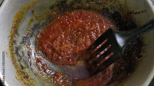 A chef is preparing sambal in a wok. This spicy relish is a commonly served dish essential to Malaysian cuisine.