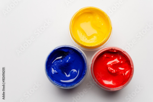 Artist's gouache, top view. Three open bottles of gouache for painting, fresh new paints ready for painting on a white background
