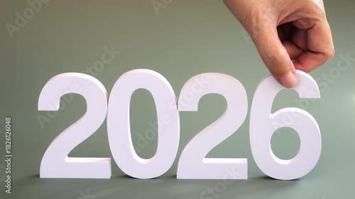 hand pick up the number 5 and place the number 6 in it place., changing from year 2025 to 2026 for new year sign on green background, 2026 New Year celebration transition from 2025 to 2026 concept