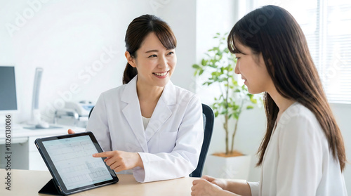Female doctor explaining diagnosis to patient using tablet healthcare consultation in modern clinic medical professional showing test results